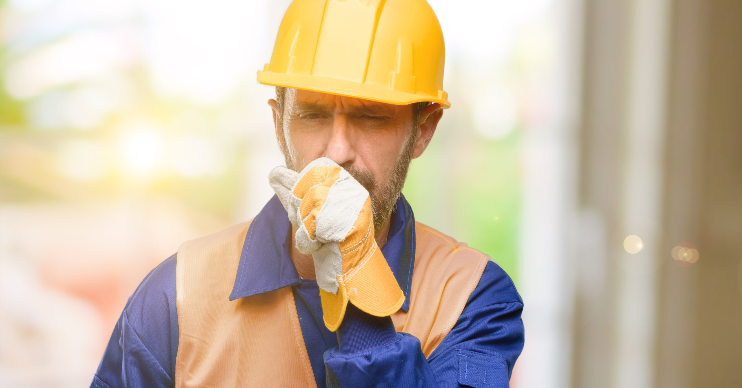 Image of a man in his construction uniform with his fist over his mouth