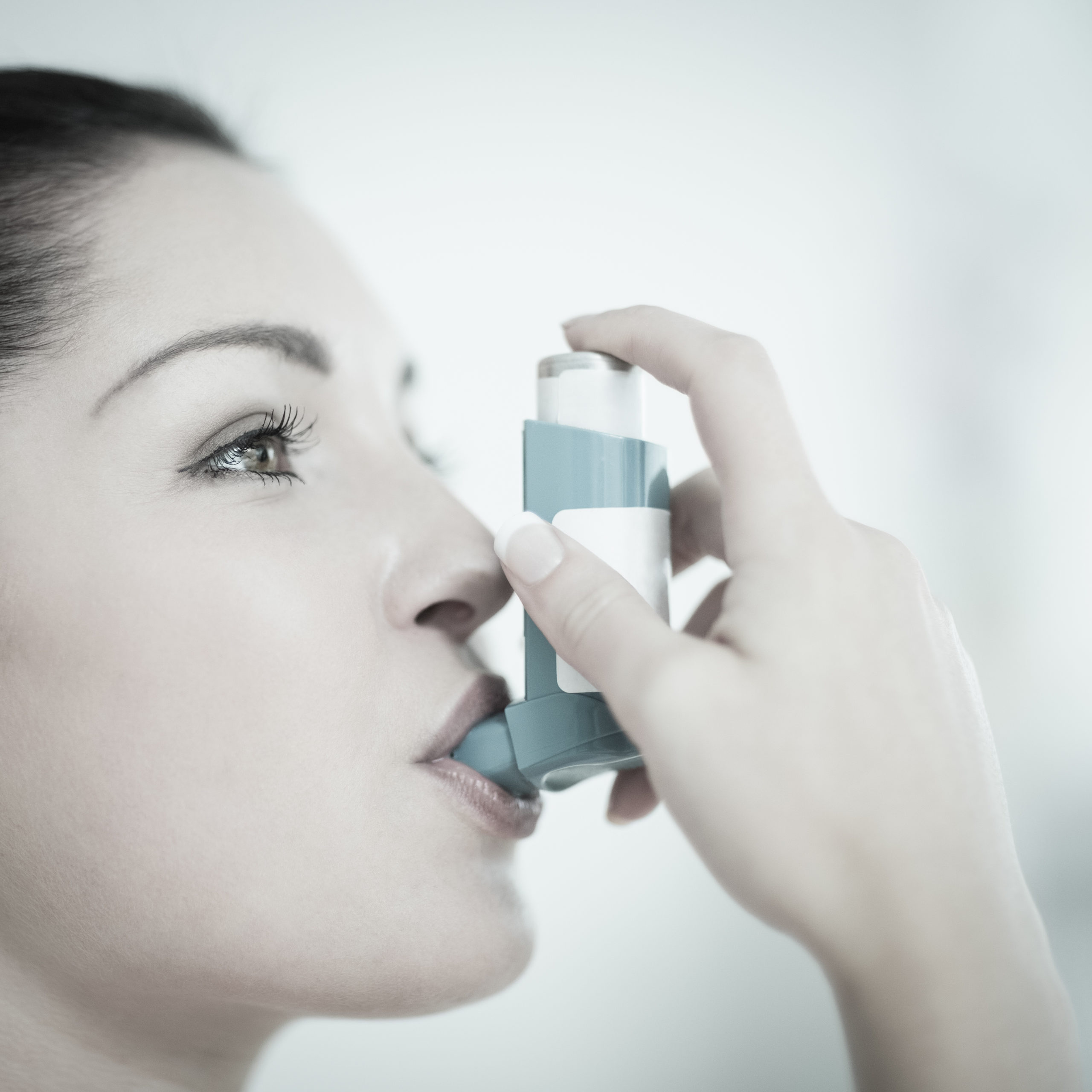 Image of a woman holding an inhaler to her mouth