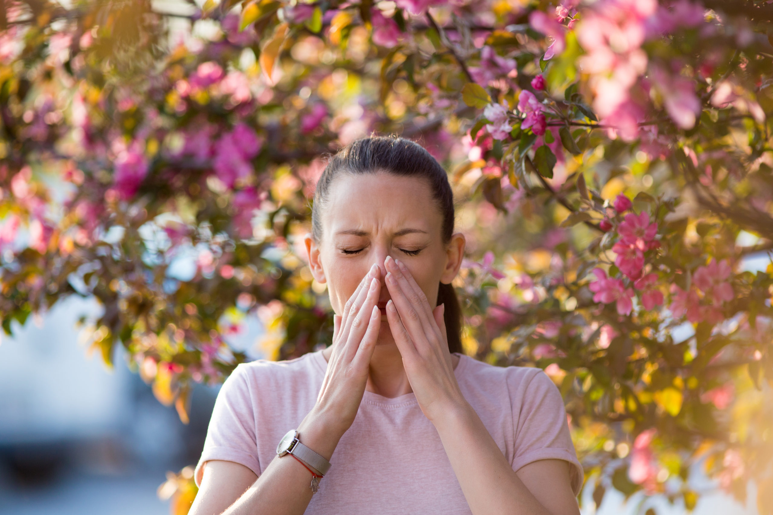 Image of a woman sneezing into her hands