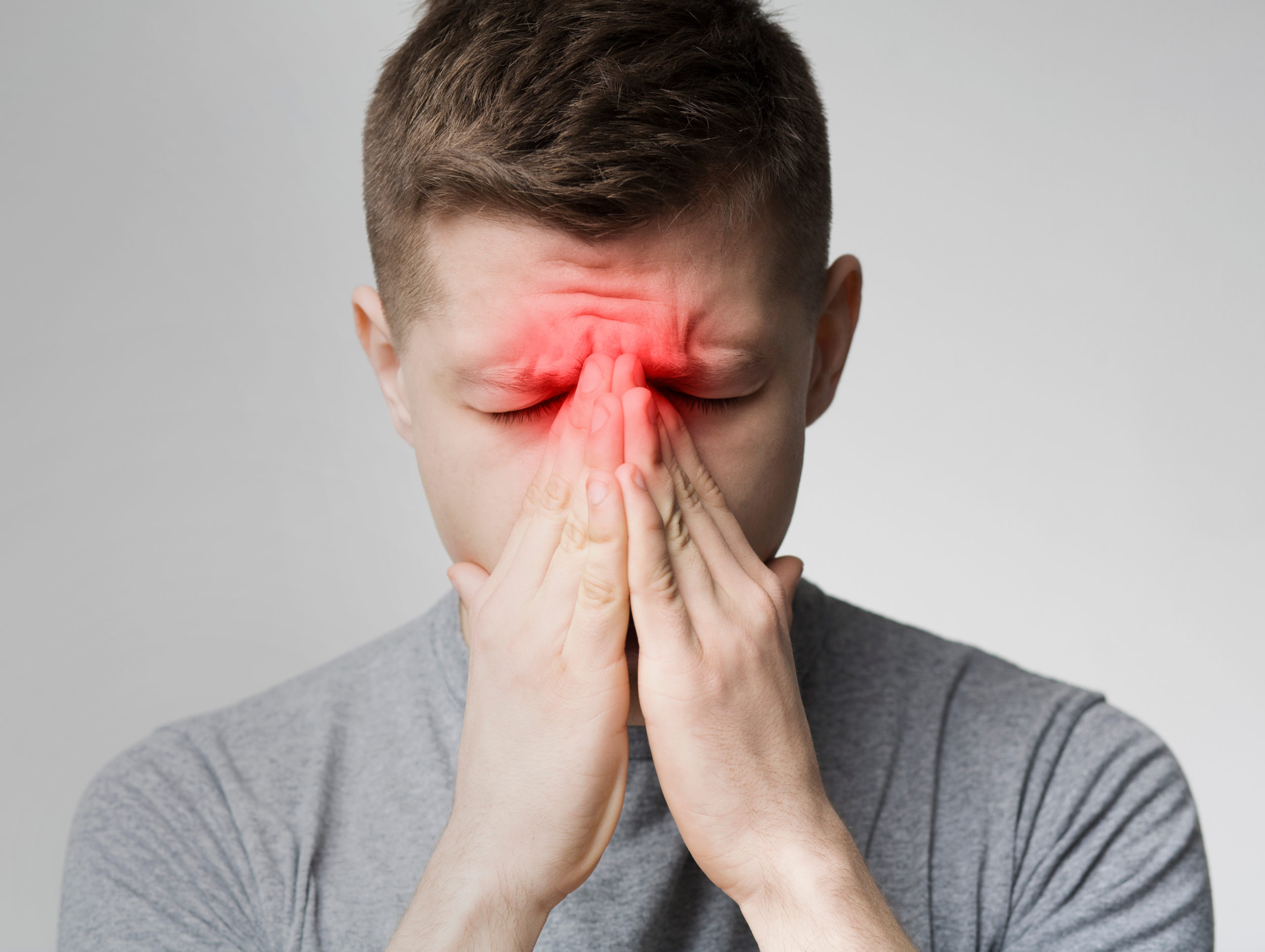Image of a man clasping his nose between his hands with a red aura indicating pain